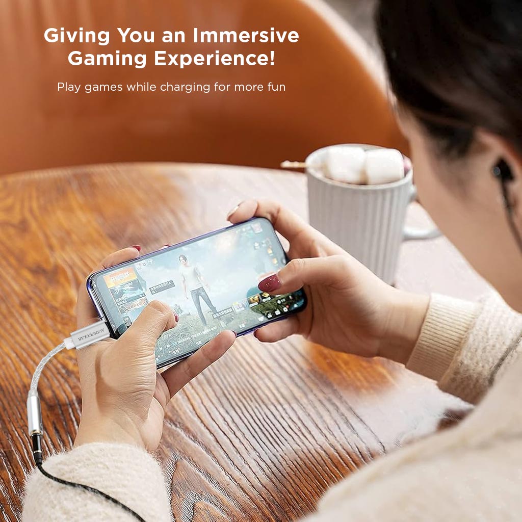 User gaming with AUDIOCULAR D07 DAC Dongle, enjoying immersive sound via USB-C to 3.5mm adapter while charging the device.