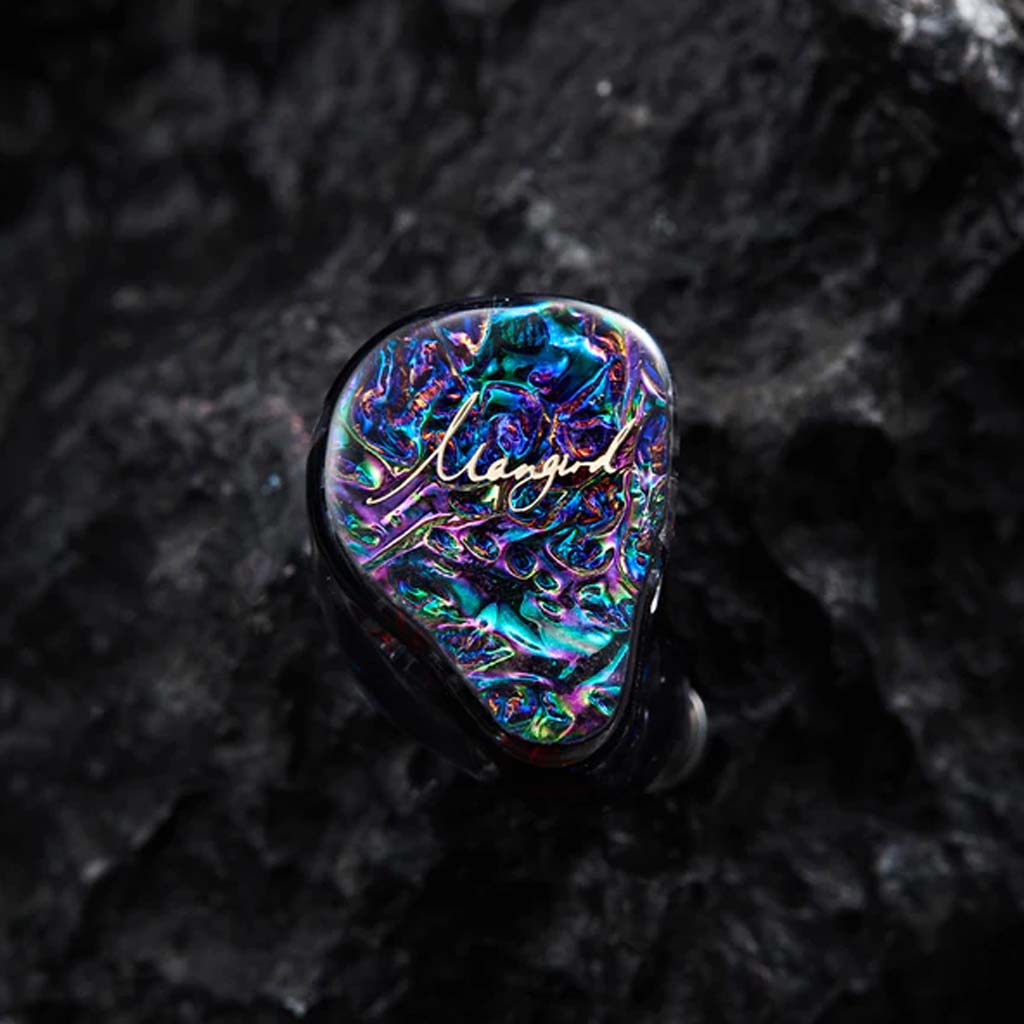 Close-up of Mangird Top Pro IEM on black rock surface, highlighting its artistic multicolor faceplate and premium build quality.