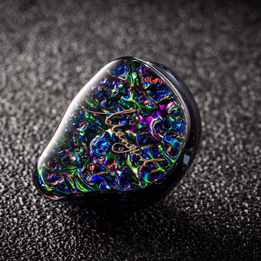 Single Mangird Top Pro IEM on textured surface, showcasing its intricate faceplate design and high-end in-ear monitor aesthetics.