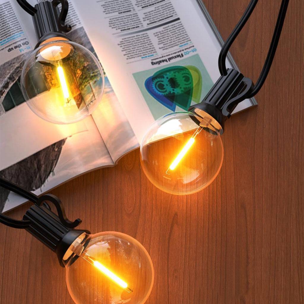 TECPHILE G40 outdoor string lights with waterproof and shatterproof bulbs, emitting a warm glow on a wooden surface. Ideal for patios and gardens.