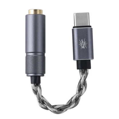 Close-up of the Kiwi Ears AD1 Pro portable headphone DAC and amplifier with a sleek gray finish and gold accents, showing the USB-C port and braided cable