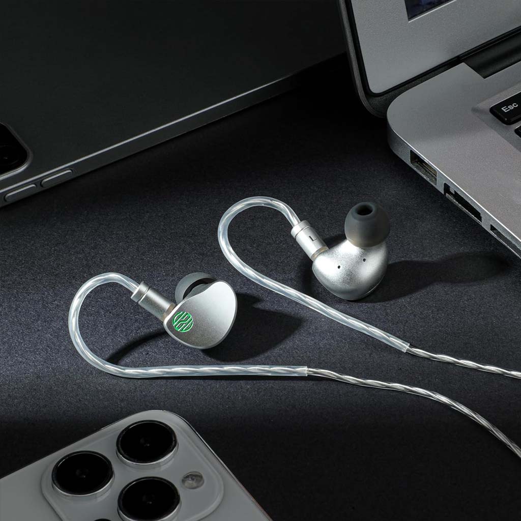 Soratune BI02 IEMs placed beside a laptop and smartphone, ideal for professional audio use and everyday listening on the go.