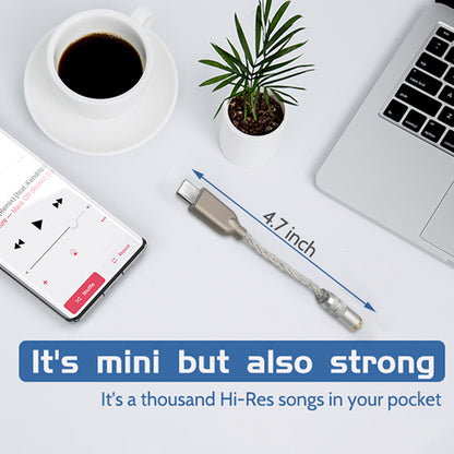 Compact AUDIOCULAR D10 DAC Dongle measuring 4.7 inches, shown beside laptop and coffee cup, emphasizing portability and strength.