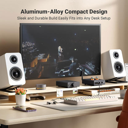 Fosi Audio Q6 DAC in a desktop setup with speakers and monitor, showcasing its compact aluminum-alloy build for audiophile environments.
