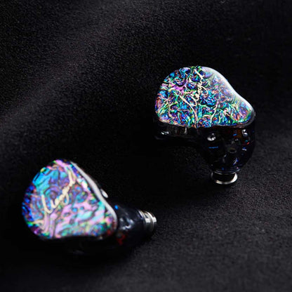 Pair of Mangird Top Pro IEMs with shimmering faceplates placed on black fabric, emphasizing luxury design and craftsmanship.