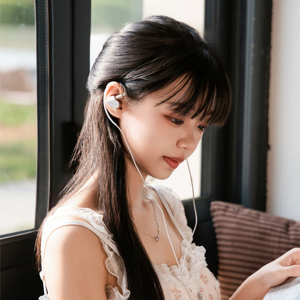 Woman wearing TANCHJIM Fission IEMs, showcasing ergonomic fit and stylish design for immersive and comfortable listening.