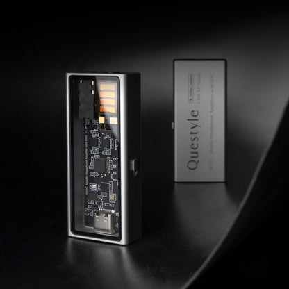 QUESTYLE M15C portable DAC/Amp displayed in a dark setting, highlighting its transparent panel and premium CNC-machined aluminum finish.