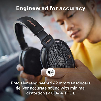 User holding HD 660S2 headphones with 42mm transducers, engineered for accurate sound reproduction and minimal distortion.