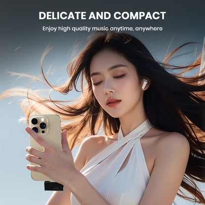Woman using TempoTec LHDC ONE Bluetooth Transmitter with smartphone, enjoying high-quality wireless music outdoors.