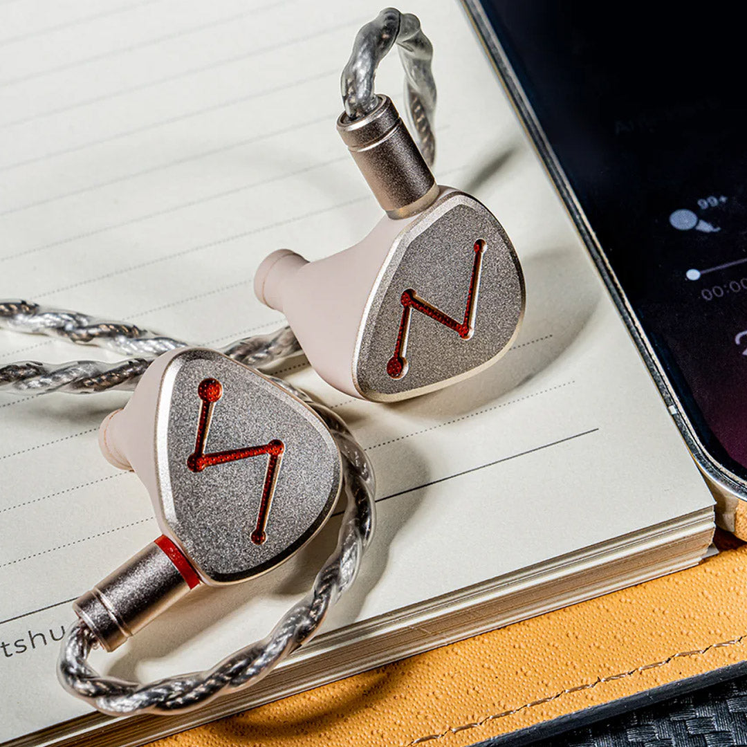 Close-up of LETSHUOER DZ4 Hi-Fi IEM resting on a notebook, showcasing its premium metal faceplate and ergonomic design.