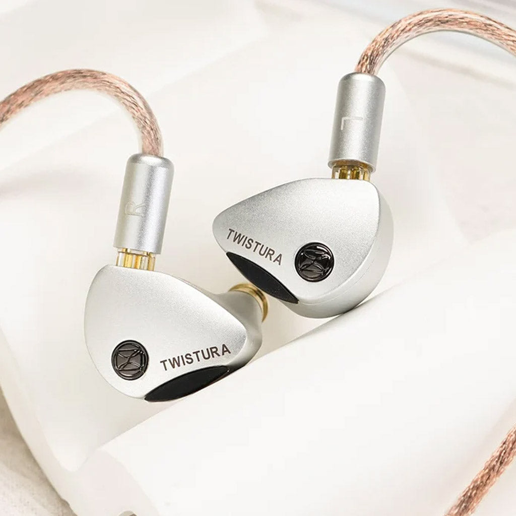 Close-up of TWISTURA Woodnote IEMs with silver finish and logo, highlighting premium build and detachable cable connectors.