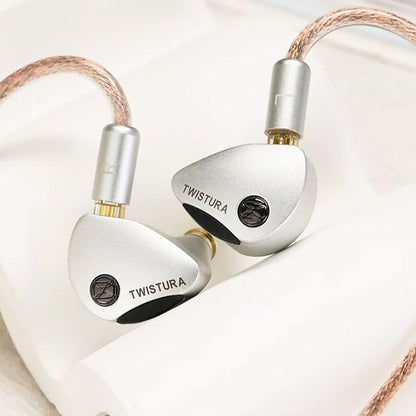 Close-up of TWISTURA Woodnote IEMs with silver finish and logo, highlighting premium build and detachable cable connectors.