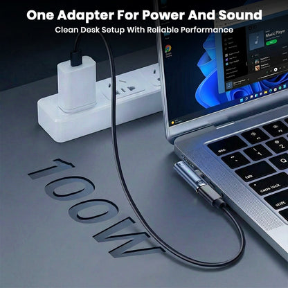 AUDIOCULAR A14X adapter on a desk setup, providing both power and sound through a single USB-C connection.